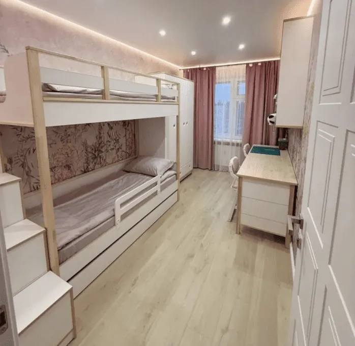 Детская комната с двухъярусной кроватью, рабочей зоной и шкафом, оформленная в светлых тонах